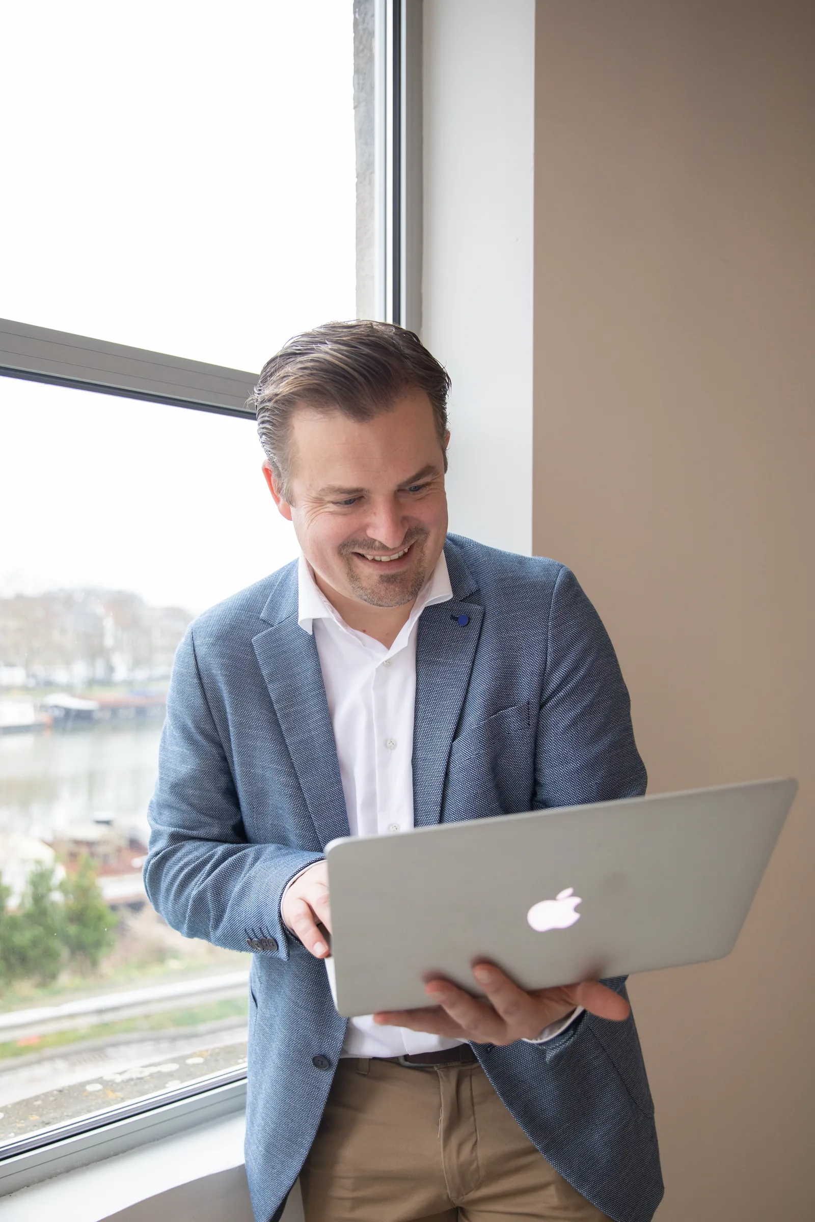 Thomas D'Aubioul, fotograaf en videograaf van Webstrive Studio, met laptop bij het raam